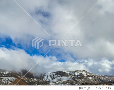 Snowy mountain landscape beneath dramatic cloudy sky Snowy mountain landscape beneath dramatic cloudy sky 140782635