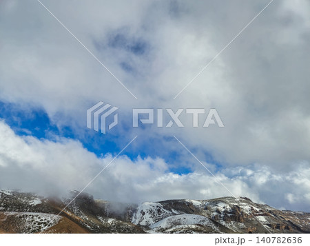 Snowy mountain landscape beneath dramatic cloudy sky Snowy mountain landscape beneath dramatic cloudy sky 140782636