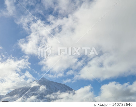 Snowy mountain peak beneath cloudy blue sky Snowy mountain peak beneath cloudy blue sky 140782640