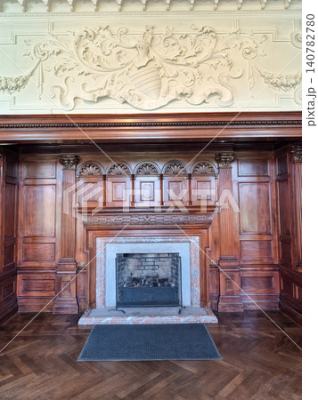 Elegant ornate fireplace in classic wood-paneled room 140782780