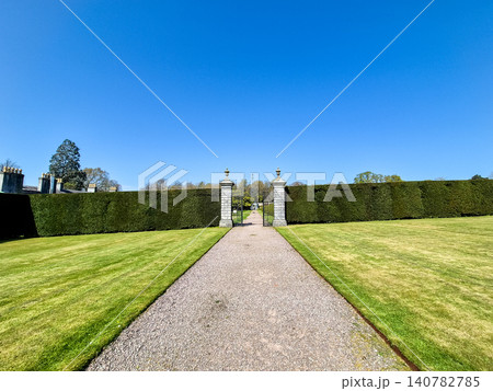 Formal garden path leading to gated hedge entrance Formal garden path leading to gated hedge entrance 140782785