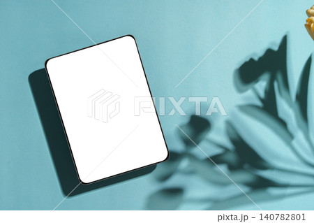 Tablet mockup with blank white screen on light blue background with plant shadows Tablet mockup with blank white screen on light blue background with plant shadows 140782801