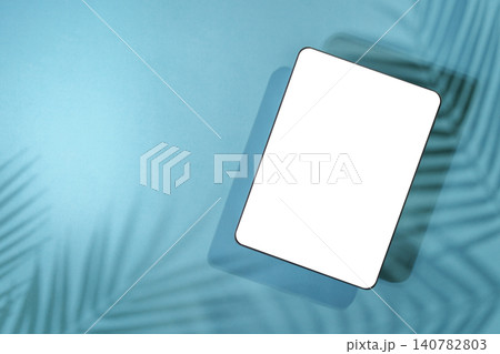 Digital tablet mockup with blank white screen on blue background with palm leaf shadows Digital tablet mockup with blank white screen on blue background with palm leaf shadows 140782803