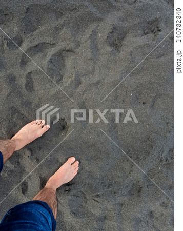 Bare feet walking on dark beach sand Bare feet walking on dark beach sand 140782840