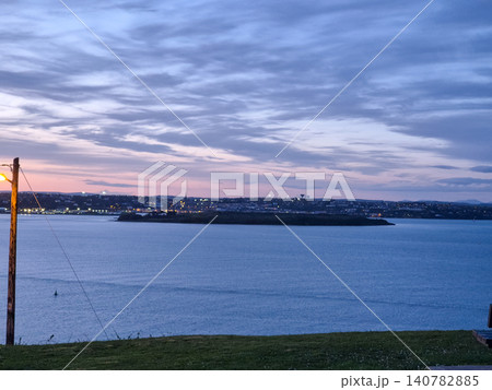 Twilight coastal landscape with calm water and city lights 140782885