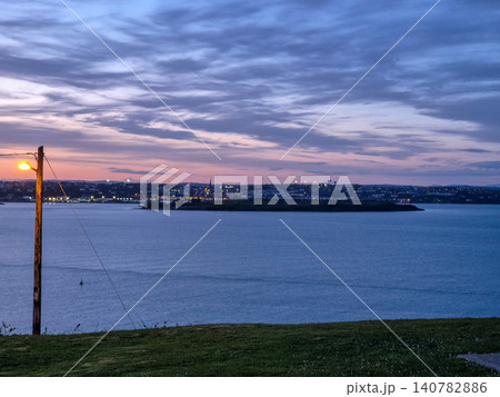 Dusk seascape with distant city lights and cloudy sky Dusk seascape with distant city lights and cloudy sky 140782886