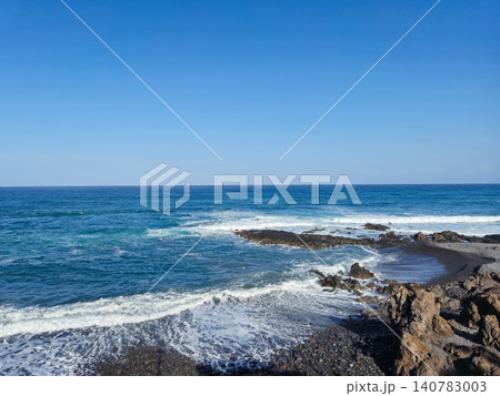 Rocky Ocean Shoreline Under Clear Blue Sky 140783003