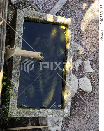 Stone water tank with bamboo spout outdoors Stone water tank with bamboo spout outdoors 140783128
