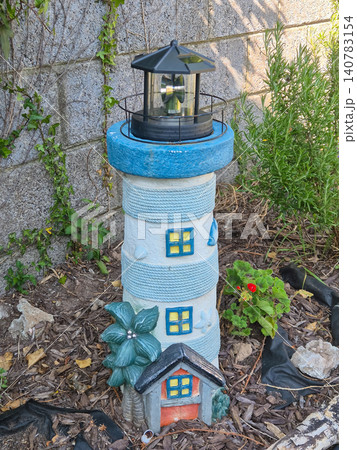 Decorative lighthouse garden ornament in backyard landscaping Decorative lighthouse garden ornament in backyard landscaping 140783154