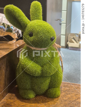 Green moss bunny figurine on wooden shelf 140783279
