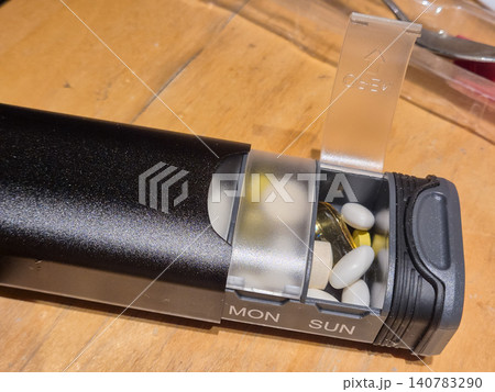 Weekly pill organizer with opened medication compartment 140783290