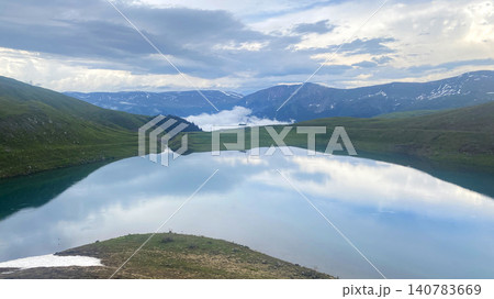 Calm waters of Karagoli Lake reflecting dramatic clouds and mountain ridges on a summer evening in Adjara, Georgia Calm waters of Karagoli Lake reflecting dramatic clouds and mountain ridges on a summer evening in Adjara, Georgia 140783669