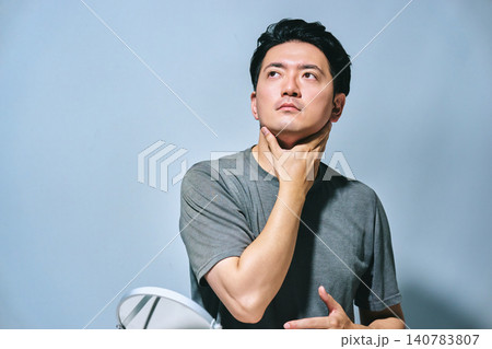 手で顎を触り上を見上げる30代の日本人の男性のスキンケア中の会社員 140783807