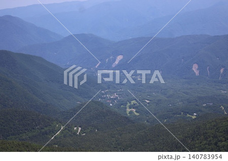 山頂から見下ろす幾重にも重なる青い山並みと谷あいの集落の風景 山頂から見下ろす幾重にも重なる青い山並みと谷あいの集落の風景 140783954
