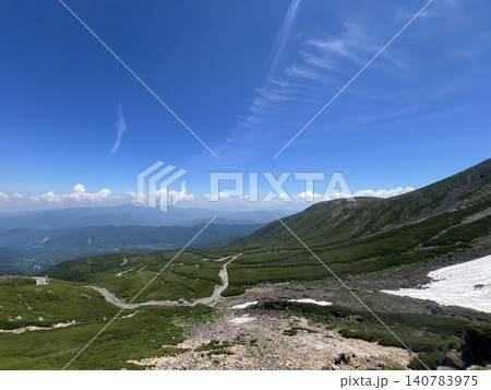 快晴の青空と眩しい光 雄大な山並みを見下ろす山岳道路と残雪の夏景色 140783975