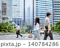 休日出勤の仕事で都会の道路の横断歩道を歩く30代の日本人のビジネスマンの男性会社員と行き交う人々 140784286