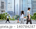 祝日に都会の高層ビル街の道路の横断歩道を歩く30代の日本人の男性の会社員と横切るデート中のカップル 140784287