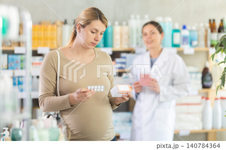Pregnant woman choosing pills with help of pharmacist 140784364