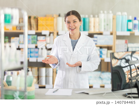 Female pharmacist standing at counter with welcoming gesture 140784465