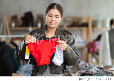 Female shopper selects panties in fashionable clothing boutique. Female shopper selects panties in fashionable clothing boutique. 140784534