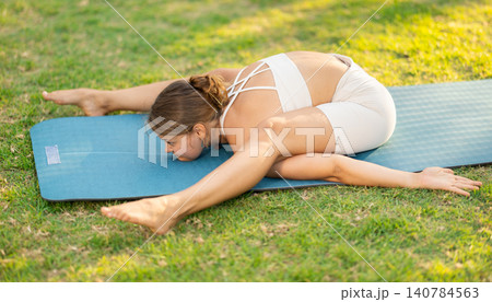 Girl in park on green grass of lawn performs Supta Kurmasa Girl in park on green grass of lawn performs Supta Kurmasa 140784563