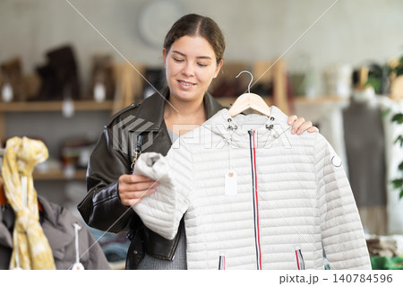 Young woman choosing down jacket in clothing store Young woman choosing down jacket in clothing store 140784596