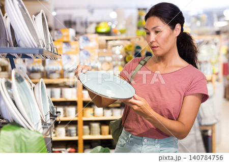 Attentive woman choosing new crockery in dinnerware store closeup 140784756