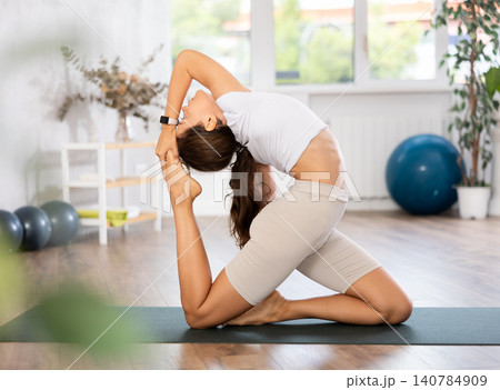 Experienced girl, fitness club teacher, performs crescent moon asana, anjaneyasana 140784909