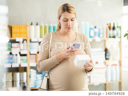 Pregnant woman scanning qr code of pills Pregnant woman scanning qr code of pills 140784926