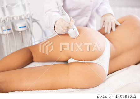 Cosmetologist using cold hammer during hardware procedure on female buttocks Cosmetologist using cold hammer during hardware procedure on female buttocks 140785012