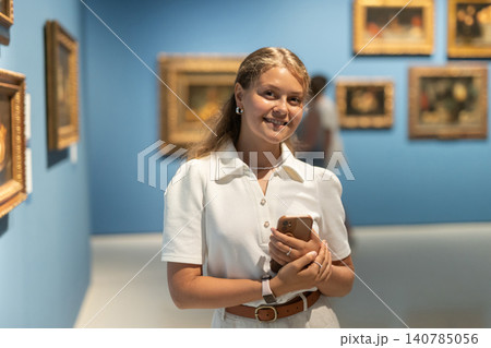Woman with phone in hands view pictures and icons in museum hall Woman with phone in hands view pictures and icons in museum hall 140785056