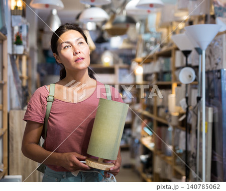 Woman choosing table lamp in store Woman choosing table lamp in store 140785062