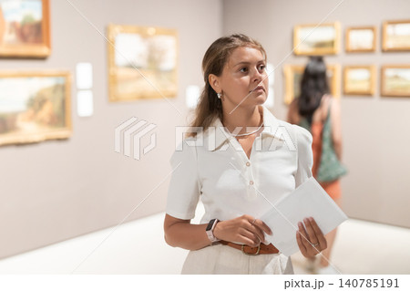 Woman with sheet piece of paper in hands view pictures and icons in museum hall 140785191