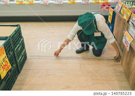 メジャーで床を測る食品スーパーの男性店員 140785223