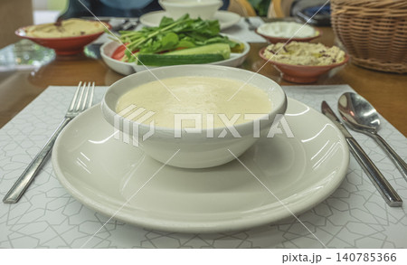 Bowl of fresh homemade cream soup puree with bread and vegetables on wooden table. Creamy garlic soup served at the restaurant. Eating healthy concept. Nobody, selective focus Bowl of fresh homemade cream soup puree with bread and vegetables on wooden table. Creamy garlic soup served at the restaurant. Eating healthy concept. Nobody, selective focus 140785366