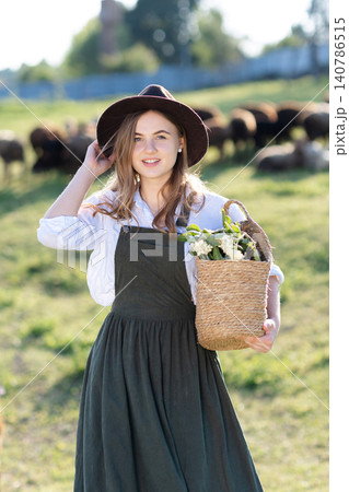 Farmer walking with goats and holding basket in front of goats herd Farmer walking with goats and holding basket in front of goats herd 140786515