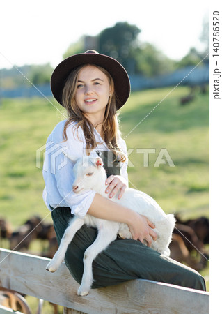 Young farmer woman holding a baby goat in a farm 140786520