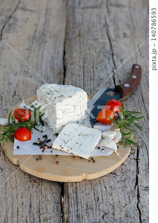 Fresh cheese with herbs served on wooden board with rosemary, tomatoes, garlic and pepper Fresh cheese with herbs served on wooden board with rosemary, tomatoes, garlic and pepper 140786593