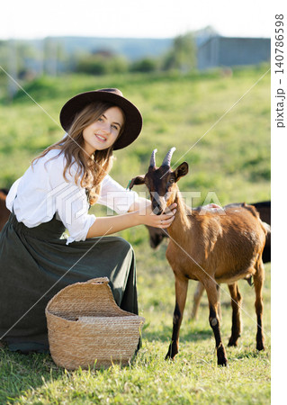 Farmer woman petting a goat in a field Farmer woman petting a goat in a field 140786598