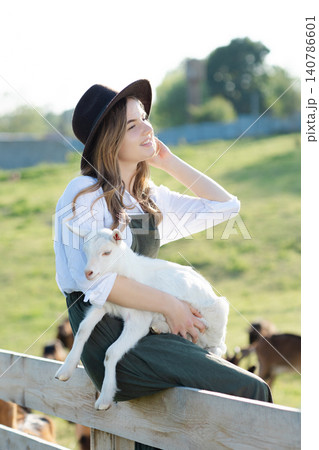Young farmer woman holding a baby goat in a farm 140786601