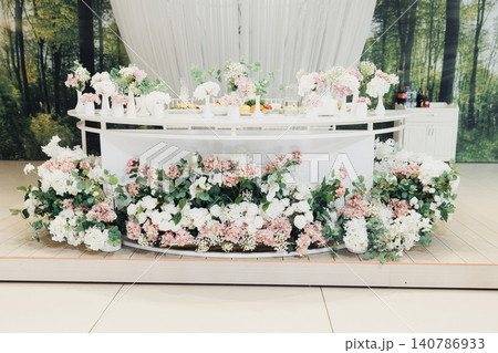 Elegant table adorned with delicate flowers and soft pastel blooms Elegant table adorned with delicate flowers and soft pastel blooms 140786933