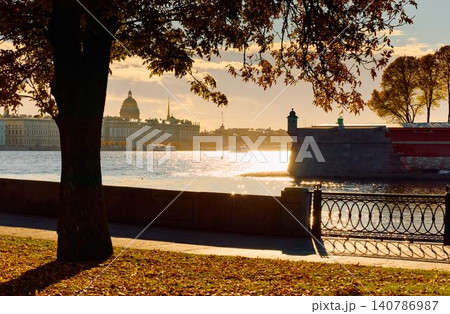 Isaac cathedral, Winter Palace, picturesque metal railings with a double-headed eagle and the crown of the Russian Empire on embankment in St. Petersburg, autumn sunset, incredible sun glare, Russia Isaac cathedral, Winter Palace, picturesque metal railings with a double-headed eagle and the crown of the Russian Empire on embankment in St. Petersburg, autumn sunset, incredible sun glare, Russia 140786987