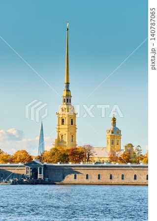 The golden spire of the Peter and Paul Fortress through yellow leaves in Saint-Petersburg - Russia at sunny autumn day, cross with angel on spire, red leaves, sunset, clear sky 140787065