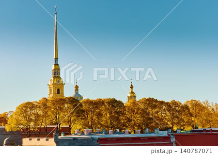 The golden spire of the Peter and Paul Fortress through yellow leaves in Saint-Petersburg - Russia at sunny autumn day, cross with angel on spire, red leaves, sunset, clear sky The golden spire of the Peter and Paul Fortress through yellow leaves in Saint-Petersburg - Russia at sunny autumn day, cross with angel on spire, red leaves, sunset, clear sky 140787071