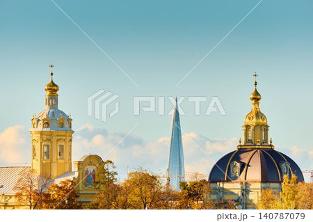 The golden spire of the Peter and Paul Fortress through yellow leaves in Saint-Petersburg - Russia at sunny autumn day, cross with angel on spire, red leaves, sunset, clear sky 140787079