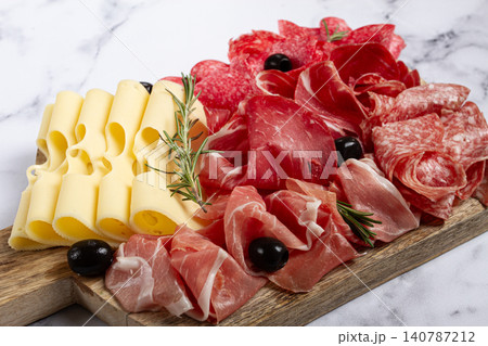 Assorted meat, appetizer, prosciutto, salami and ham, with maasdam cheese and olives, on a wooden board, breakfast, top view, close-up, no people Assorted meat, appetizer, prosciutto, salami and ham, with maasdam cheese and olives, on a wooden board, breakfast, top view, close-up, no people 140787212