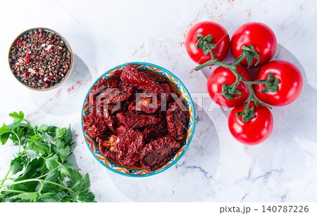 Dried tomatoes, in a bowl with fresh herbs and spices, on a white marble surface, no people Dried tomatoes, in a bowl with fresh herbs and spices, on a white marble surface, no people 140787226