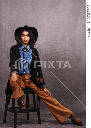 Portrait, cowgirl or woman in studio, wild west culture and cool fashion in clothing on grey background. Young female person, western lady and stylish model with pride, boho style and chair stool Portrait, cowgirl or woman in studio, wild west culture and cool fashion in clothing on grey background. Young female person, western lady and stylish model with pride, boho style and chair stool 140787703