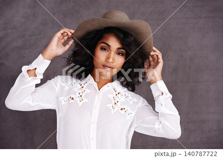 Portrait, studio and woman with cowboy fashion, confidence and relax with girl in stetson hat. Rodeo, western style and face Mexican model with cowgirl culture, wild west clothes and grey background Portrait, studio and woman with cowboy fashion, confidence and relax with girl in stetson hat. Rodeo, western style and face Mexican model with cowgirl culture, wild west clothes and grey background 140787722