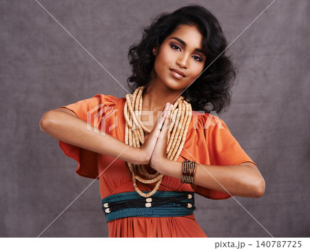 Indian woman, fashion and smile with jewelry in studio on grey background with hands together and dress. Portrait, female person and outfit with confidence in traditional necklace and creative look 140787725